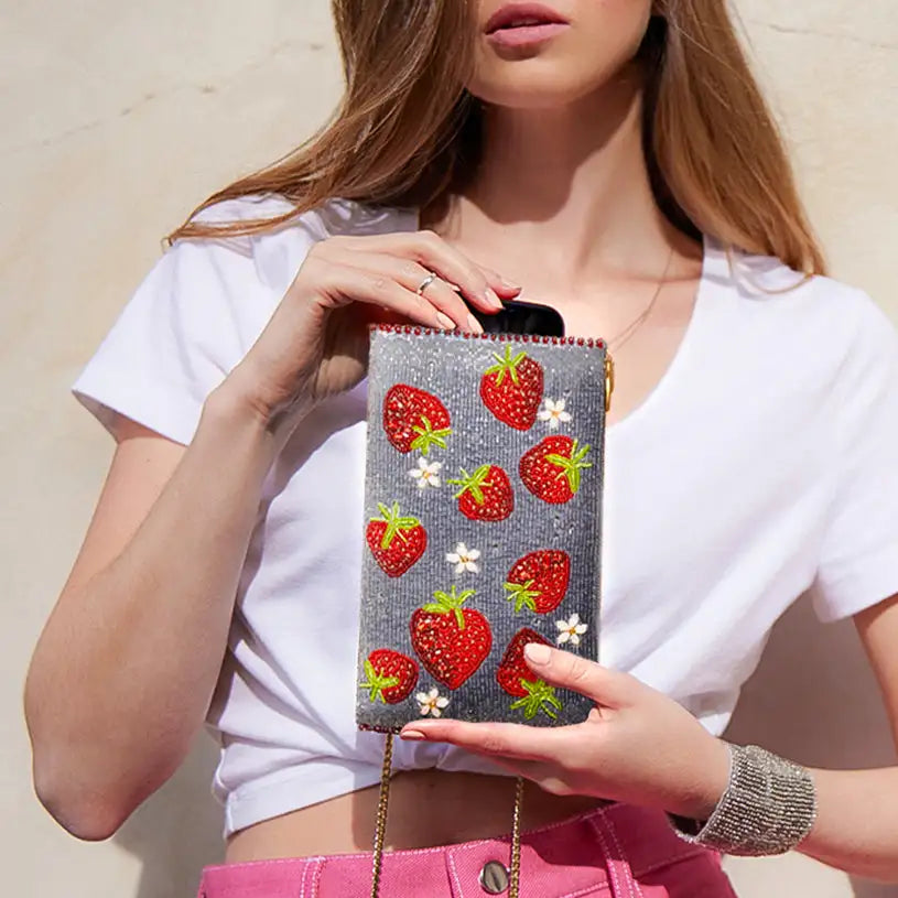 A glittery gray clutch adorned with red strawberry and white flower appliqués.