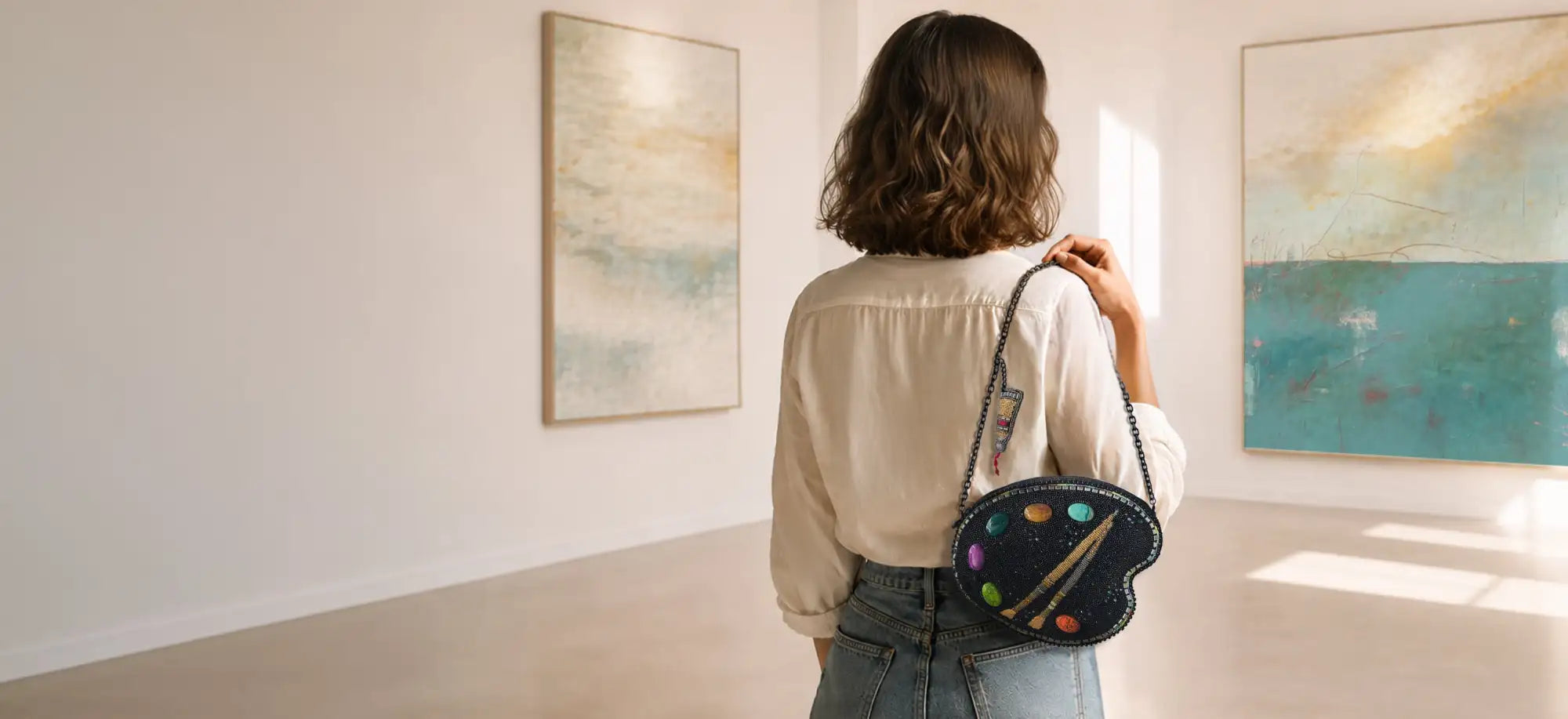 Black heart-shaped painter’s palette crossbody bag with colorful circular accents and a gold paintbrush design.