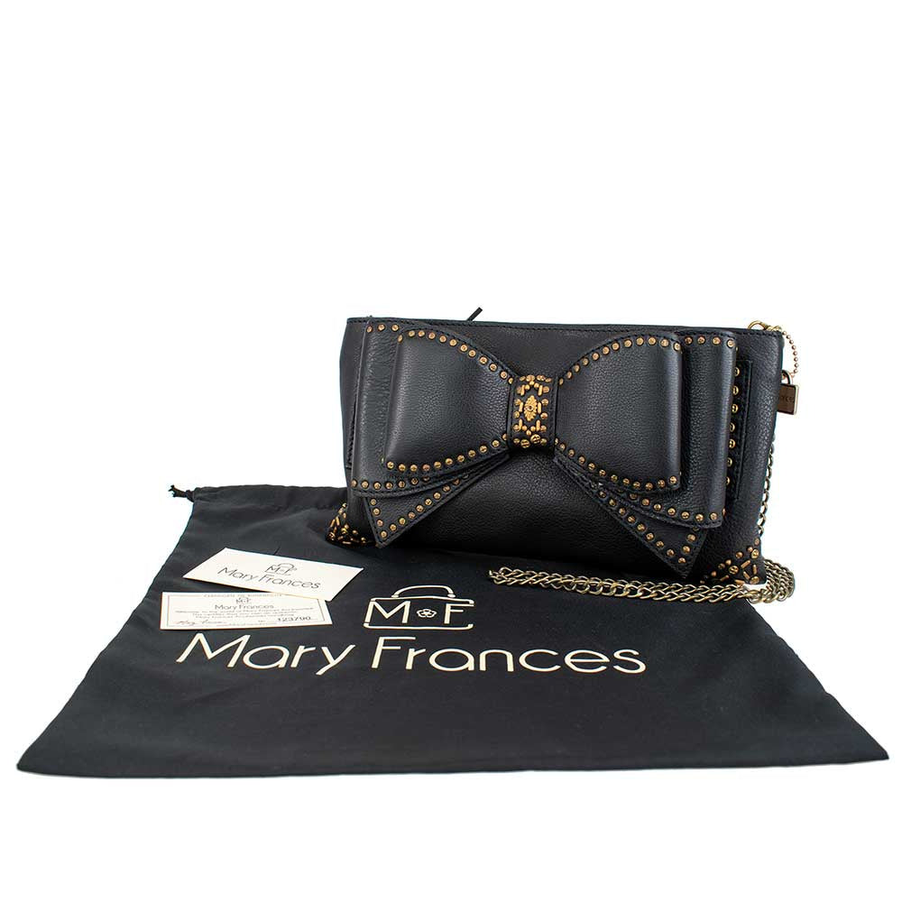 Black leather clutch bag with a decorative studded bow design and chain strap.