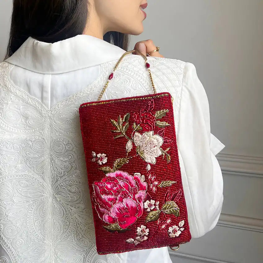 Embroidered red clutch bag with floral design.