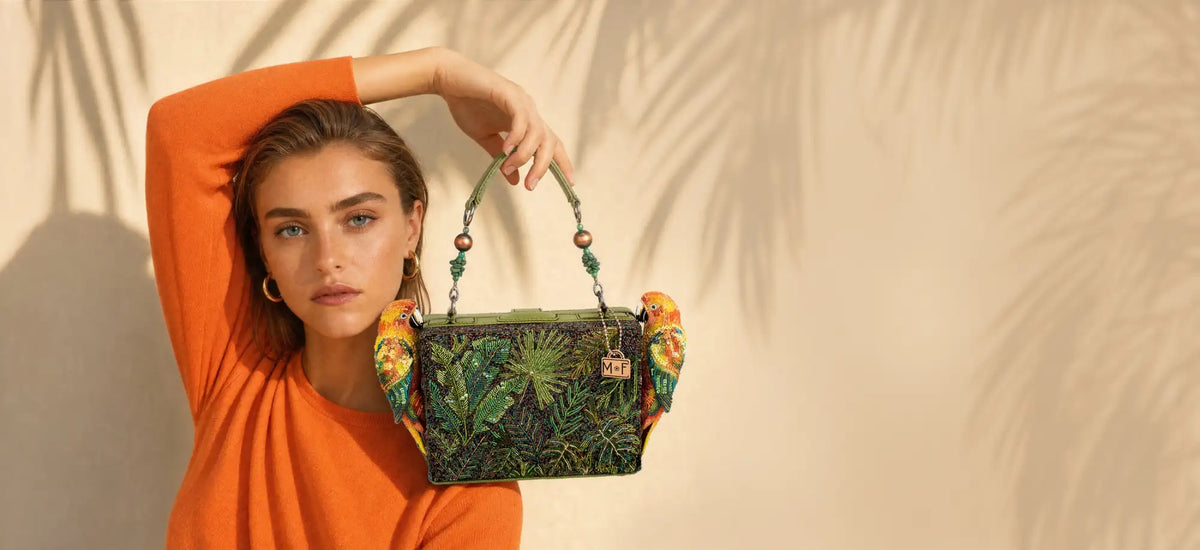 Green beaded handbag adorned with tropical leaf patterns and colorful parrot embellishments.
