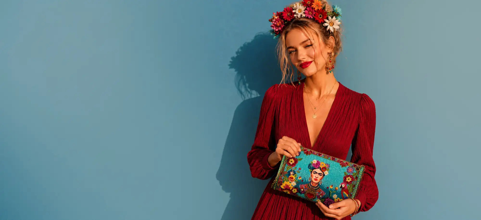 A vibrant turquoise clutch adorned with intricate floral embroidery and a detailed portrait of frida kahlo.